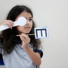 Menina segura marcação na frente de um olho para fazer teste de visão
