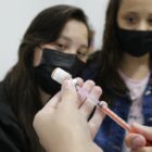 mãe e filha observam vacina sendo preparada