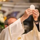 Celebrante católico segura uma hóstia