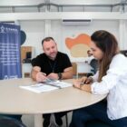 Técnico orienta cidadã em uma mesa com papéis em cima