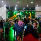 Alunas da terceira idade dançam, vestidas de caipira, na frente de um palco