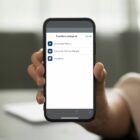 Pessoa segura um celular cuja tela está no app Joinville Fácil