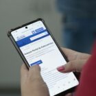Mulher mexe em celular em página da prefeitura