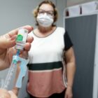 Paciente observa profissional da saúde manipular vacina
