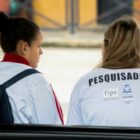 Pesquisadora sentada ao lado de mulher que responde a questionário