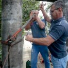 Dois trabalhadores da Prefeitura ajustam cabos em ponte interditada