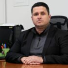 secretário Flavio está sentado, olhando para a foto