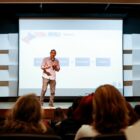 Palestrante em palco fala para plateia