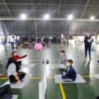 Crianças jogam vôlei sentados para vivenciarem prática paradesportiva