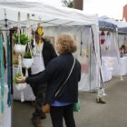 Mulher observa produtos artesanais em barraca de feira de rua