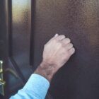 Imagem da mão de um homem batendo em uma porta