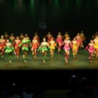 Bailarinos de danças populares se apresentam com figurino em palco