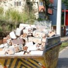 Caçamba de lixo com resíduos da construção civil em rua