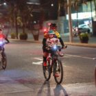 Menina anda de bicicleta com o pai sentada na cadeirinha