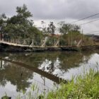 Homem passa com bicicleta pela ponte pênsil