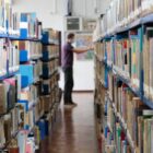 Homem procura livro em corredor de uma biblioteca