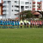 Dois times de futebol feminino em posição de respeito antes do jogo, em gramado