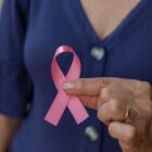 Profissional da saúde segura laço rosa, símbolo da campanha Outubro Rosa