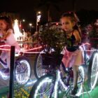 Crianças pedalam em bicicletas montadas em praça como atração natalina