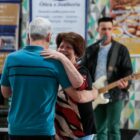 Casal de idosos dança juntos e cantor se apresenta atrás