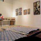 Tapetes, quadros e objetos de decoração expostos em uma galeria