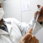 Profissional da saúde manipula injeção com vacina