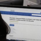 Mulher olha tela de computador na página sobre concurso