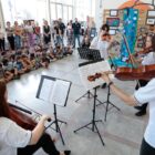 Alunos tocam instrumentos musicais observados por outros alunos