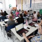 Professores, em sala de aula, com computadores prestam atenção em aula