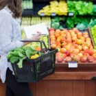 Mulher em supermercado, na área de hortifruti, com cesta