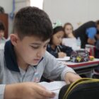 Imagem de um aluno da rede municipal, em sala de aula, escrevendo em um caderno