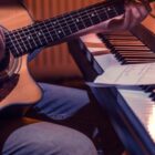 músico toca violão em frente a um piano