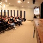 Palestrante fala no palco para plateia no auditório