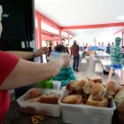 Mulher serve comida a uma criança no pátio de uma escola