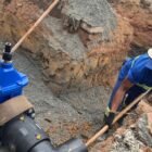 Homem de capacete trabalha em tubulação de água