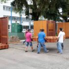 Homens carregam partes das casas de madeira que estão sendo montadas na praça