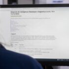 Mulher olha para tela de computador na página para se inscrever em simpósio