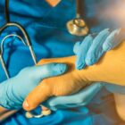 Profissional de saúde, com luvas, examina paciente