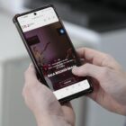 Pessoa não identificada segura celular nas mãos e acessa plataforma cultural