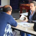 Servidora atende morador em pátio de escola