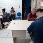 Pessoas sentadas fazem cadastro com servidores em computadores