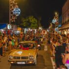 Carros antigos enfeitados para o Natal desfilam em rua e pessoas assistem das calçadas