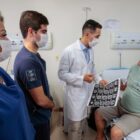 Médicos e enfermeira conversam com paciente em leito