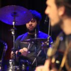 Baterista olha para outro músico em palco