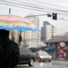 Homem segura guarda chuva em rua durante tempestade
