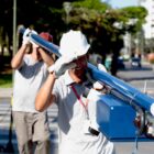 Trabalhadores uniformizados e com capacete e luvas carregam poste