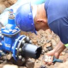 Homem, de capacete, luvas e uniforme, trabalha em tubulação