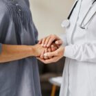 Mulher e médica se dão as mãos
