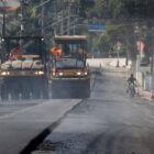 Duas máquinas andam lado a lado em rua que recebe nova pavimentação