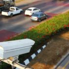 Radar de trânsito no alto de uma rua onde passam carros